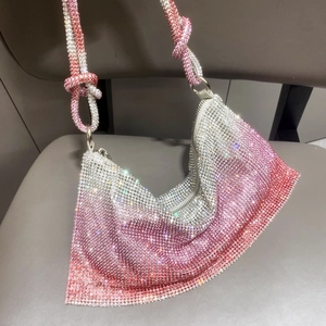 Detailed macro view of pink gradient rhinestone mesh fabric and knot strap on hobo bag