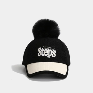 Detail of wool baseball cap featuring Vibrant Steps embroidery and large black pompom