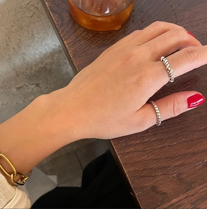 Detailed view of silver and gold irregular rings and a link bracelet on a hand