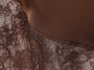 Détail du tissu en satin marron foncé avec dentelle délicate et texture lisse