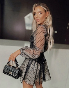 Detailed shot of black polka dot mesh dress paired with a studded quilted handbag