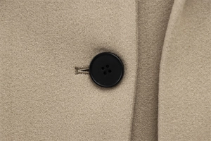 Macro detail of high-quality wool blend fabric and black resin button on beige coat