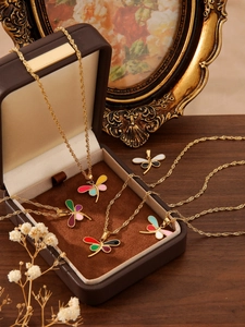 Detailed view of colorful enamel dragonfly pendants on gold-plated wavy snake chains