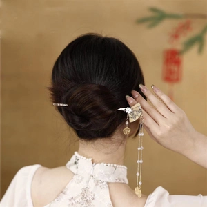Gros plan sur épingle à cheveux éventail vintage avec de longs glands en perles de nacre