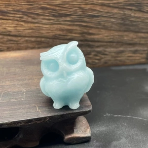 Close-up of a 3.5cm light blue natural stone owl figurine on a dark wooden base
