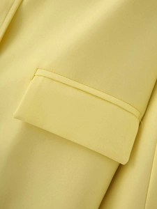 Detail of the high-quality stitching and flap pocket on this yellow satin blazer