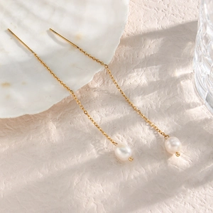 Eleganti orecchini e collana di perle dorate su una conchiglia bianca decorativa