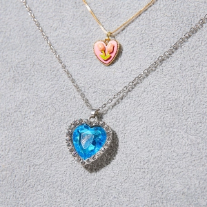 Detailed shot of gold pink tulip heart necklace and silver blue zircon heart pendant