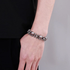 Detail of hip hop skull bracelet featuring red eyes on silver stainless steel links