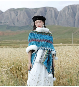 Detail van blauwe gebreide poncho met golfpatronen en witte rand van imitatiebont buiten