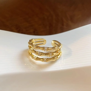 Bague triple épaisseur dorée style bambou avec zircons sur assiette blanche