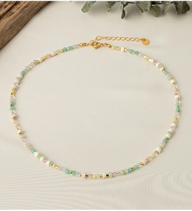 Detailed close-up of a colorful beaded necklace with mint, pink, and gold accents