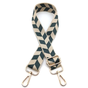 Detail of adjustable green and beige geometric woven shoulder strap with gold metal hooks
