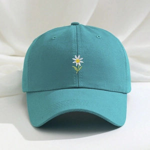 Detailed close-up of white daisy embroidery on a teal cotton baseball cap for summer