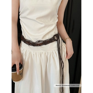 Détail d'une ceinture tressée main avec perles de santal et cordons en cuir sur robe blanche