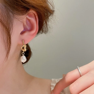 Boucles d'oreilles nœud doré avec perles d'eau douce sur un mannequin professionnel