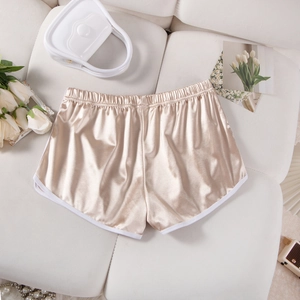 Flat lay of champagne silk satin sports shorts with white piping on a white leather texture