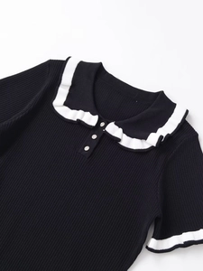 Detail of contrast knit polo shirt featuring a white ruffle collar and decorative buttons