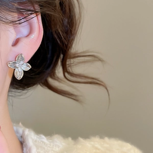 Detailed close-up of a silver flower stud earring with sparkling cubic zirconia on a model