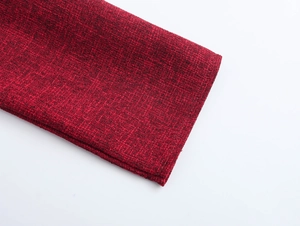 Dettaglio ravvicinato degli strati di tessuto rosso scuro e dei polsini dell'abito elegante