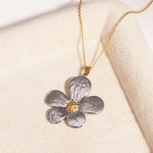 Détail du pendentif pétale argenté avec texture martelée et chaîne de collier dorée