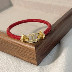 Dettaglio del bracciale rosso con fibbia dorata con cristalli su vassoio in legno