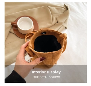 Close-up of brown suede crossbody bag with magnetic snap closure and black interior lining