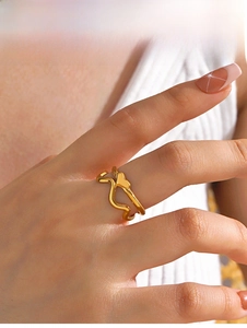 Close-up of a minimalist gold heart wave ring showing polished metallic texture on finger