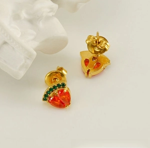 Gros plan détaillé de boucles d'oreilles fraise avec cristaux rouges et verts