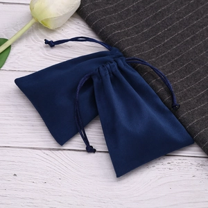 Detail of dark blue velvet jewelry pouches with drawstring on white wood background
