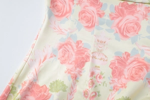Gros plan du tissu imprimé floral avec roses roses et feuilles vertes sur robe jaune