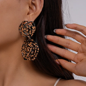 Macro view of leopard print hollow rose earrings worn by a model in a retro style