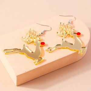 Detailed macro view of golden reindeer earrings with red nose on a geometric stone stand