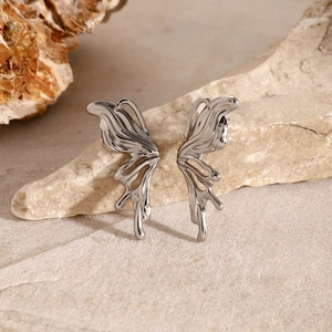 Detailed macro view of silver stainless steel butterfly wing earrings on natural stone
