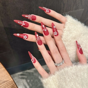 Unghie finte stiletto rosse fatte a mano con decorazioni eleganti di perle e fiori