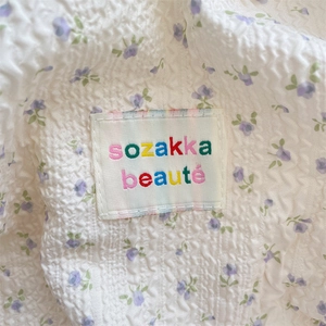 Macro shot of seersucker fabric with purple floral pattern and embroidered logo label