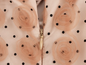 Dettaglio del fiore in mesh 3D e zip invisibile sul tessuto del vestito rosa a pois