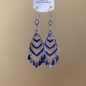 Detailed view of silver ethnic fish earrings with blue crystals and beaded tassels