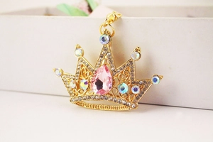 Detailed close-up of a golden crown keychain with pink teardrop crystal and colorful rhinestones