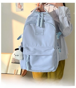 Detail view of light blue backpack featuring a cute panda plush keychain and brand logo