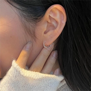 Close-up of minimalist silver hexagonal hoop earring worn by a model in a lifestyle shot