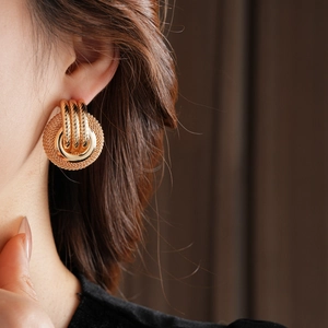 Close-up of gold hollow textured circle earrings on model with vintage metallic finish