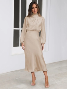 Detail of elegant champagne satin dress featuring pleated high neck and smooth texture