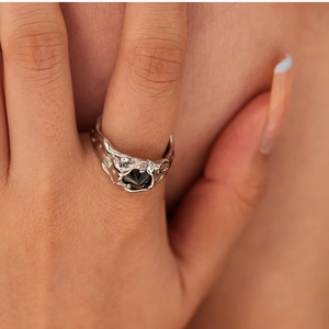 Macro view of a silver lava textured ring with a black geometric gemstone on a finger