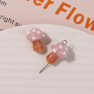 Macro shot of glass mushroom charms with pink polka dot caps and metal pins for DIY jewelry