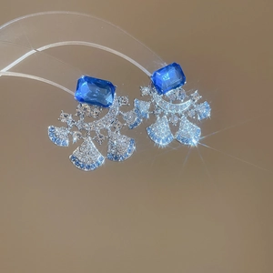 Detailed macro of silver luxury flower earrings with blue gems and micro-pave diamonds