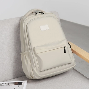 Modern cream white multi-pocket nylon backpack for students placed on a grey sofa