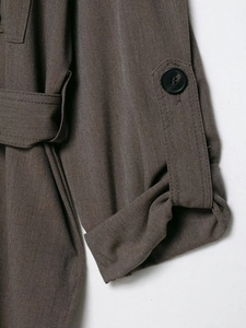 Détail du poignet d'une veste marron foncé avec bouton noir et patte de serrage fixe