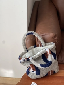 Détail du sac fourre-tout en laine d'agneau à motifs géométriques sur une surface en bois