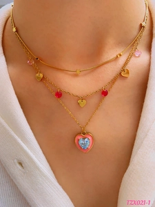 Detailed layered gold necklace with pink enamel heart and blue crystal pendant
